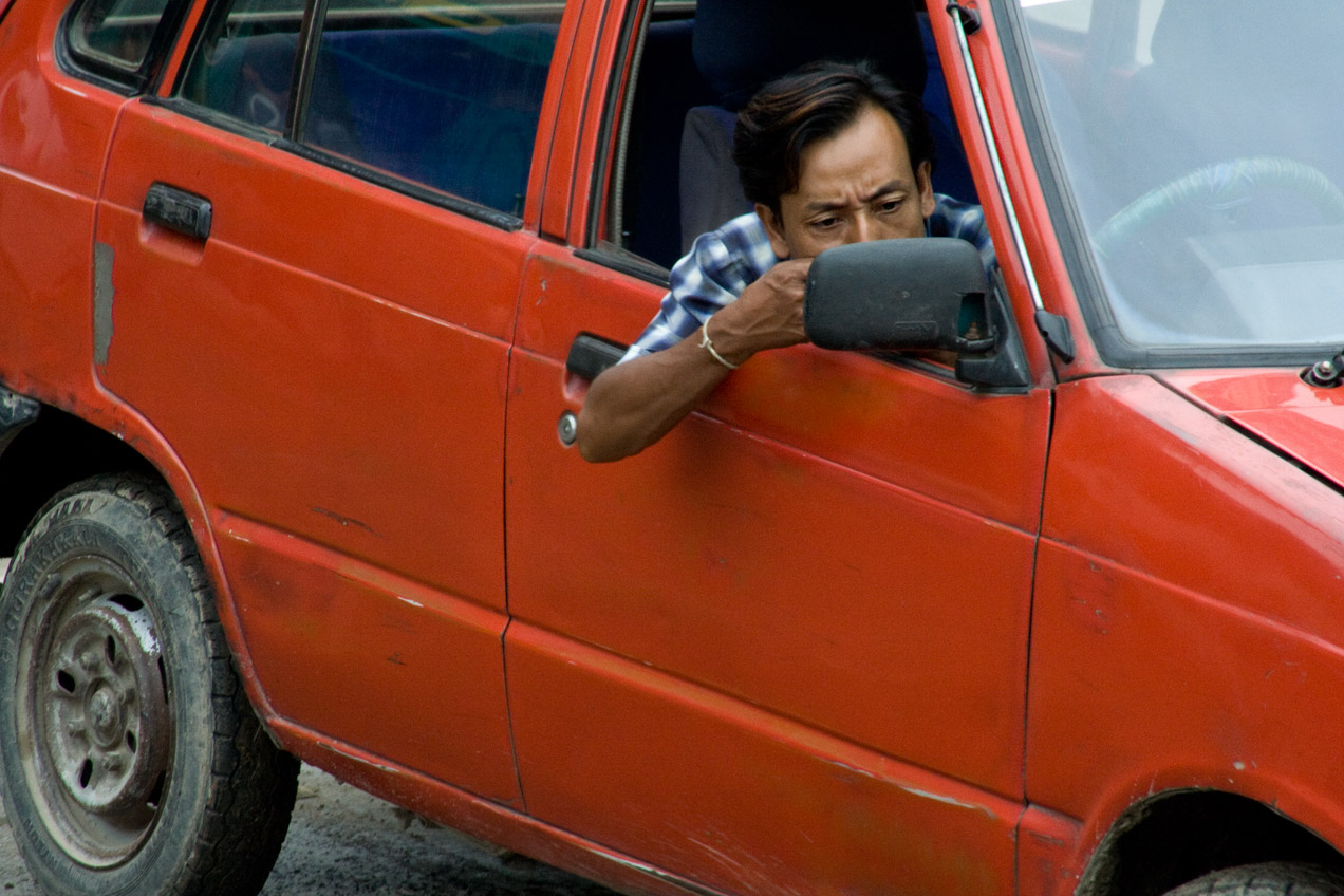 A man cleaning his teeth in the mirror of his car