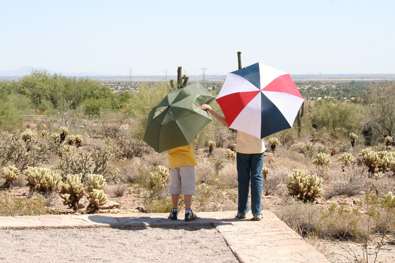 Two kids with umbrellas in the sun
